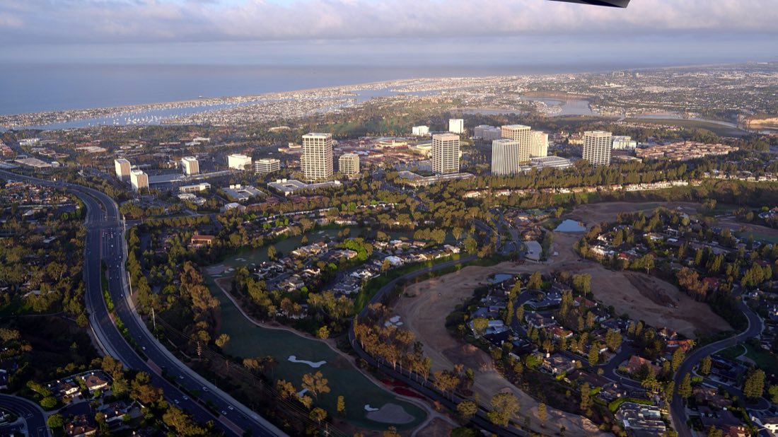 Aerial view south over Fashion Island and Newport Center at sunrise, with Newport Harbor and the Pacific Ocean beyond